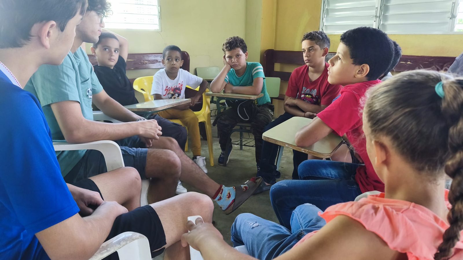 Volunteers and kids sitting in a small circle during a conversation