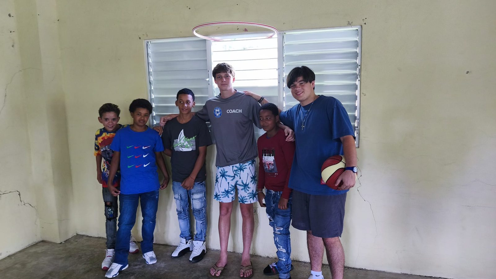 Volunteers and kids posing together with a basketball during a community visit