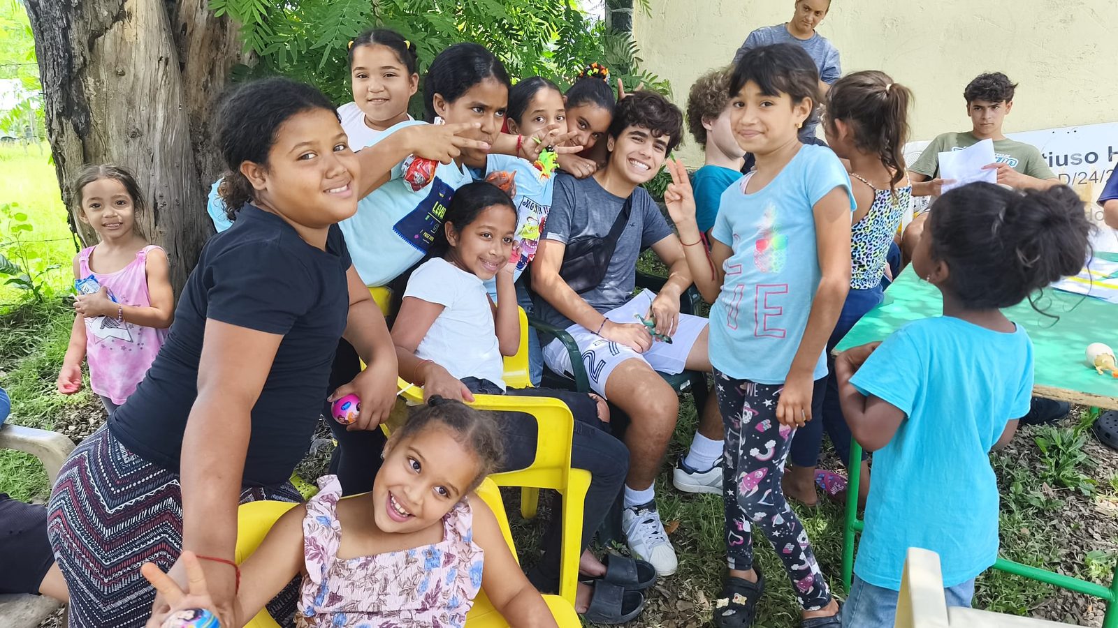 A group of kids and a volunteer gathered around an outdoor table doing crafts