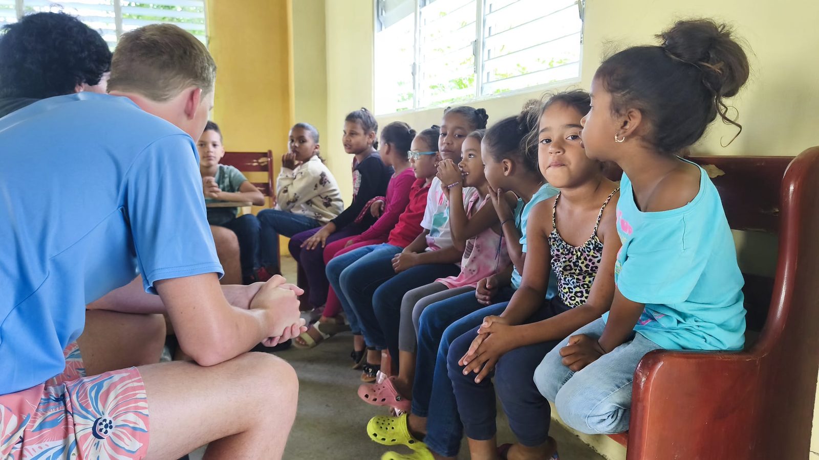 Volunteers sitting with children during a community visit in the Dominican Republic, listening attentively